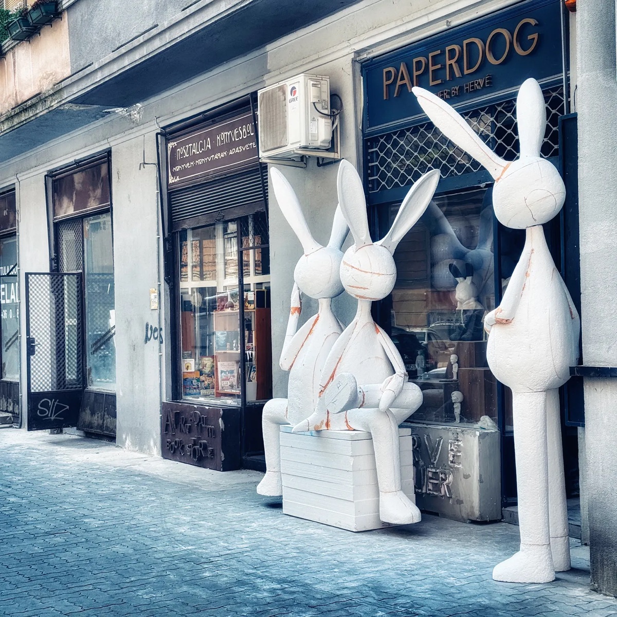 Three oversized white rabbit sculptures outside a bookshop